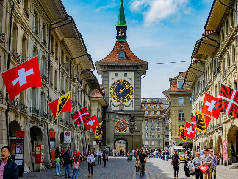 Berner Kramgasse mit dem Zytglogge-Turm und Schweizer Fahnen