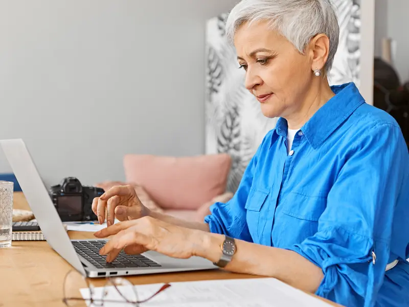 Frau mit kurzem grauem Haar arbeitet konzentriert am Laptop